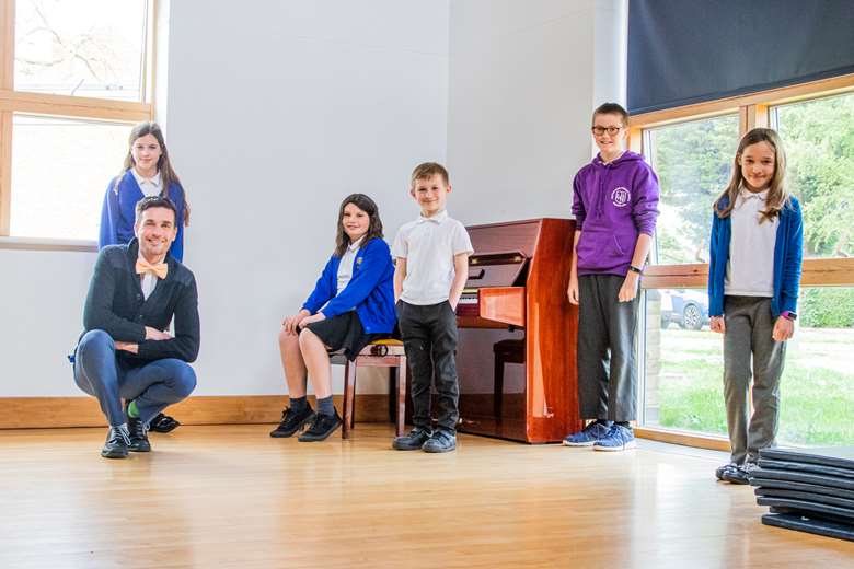 Pupils and a teacher at Hatton Park Primary School, Longstanton, stood next to a piano, donated through the Piano Equals programme (Photo: Millers Music)